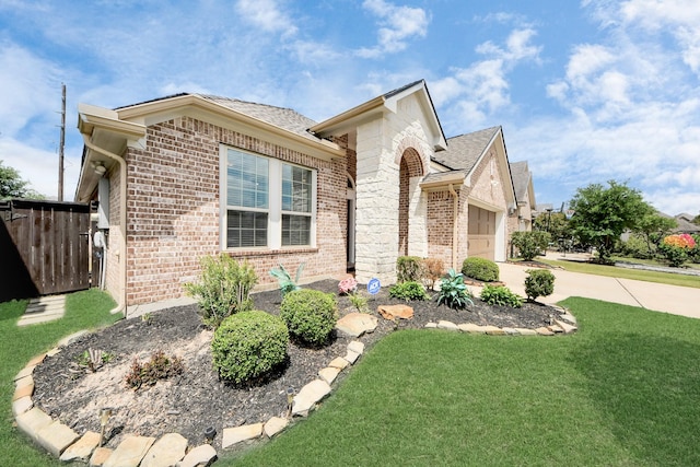 view of front of property featuring fence, driveway, brick siding, a front yard, and a garage
