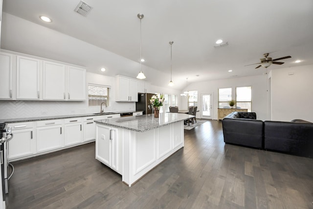 kitchen with a center island, a sink, open floor plan, white cabinetry, and stainless steel refrigerator with ice dispenser
