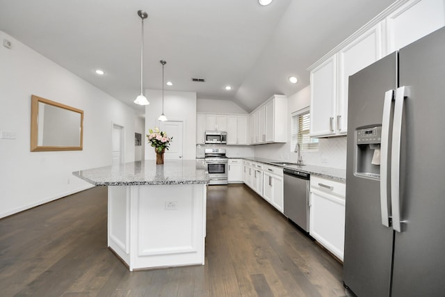 kitchen featuring white cabinets, a sink, vaulted ceiling, light stone countertops, and appliances with stainless steel finishes