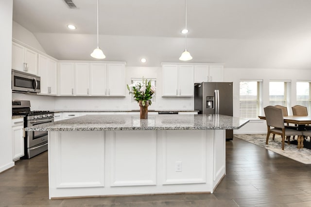 kitchen featuring white cabinets, stainless steel appliances, vaulted ceiling, recessed lighting, and a kitchen island