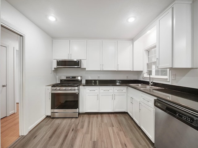 9710 Bassoon Dr, Houston, TX 77025 - kitchen featuring stainless steel appliances, light wood-style flooring, a sink, recessed lighting, and white cabinetry
