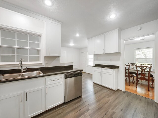 9710 Bassoon Dr, Houston, TX 77025 - kitchen with white cabinets, light wood finished floors, dark countertops, stainless steel dishwasher, and a sink