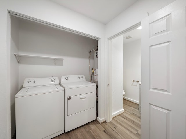 9710 Bassoon Dr, Houston, TX 77025 - washroom featuring washing machine and clothes dryer, water heater, light wood-style flooring, baseboards, and laundry area
