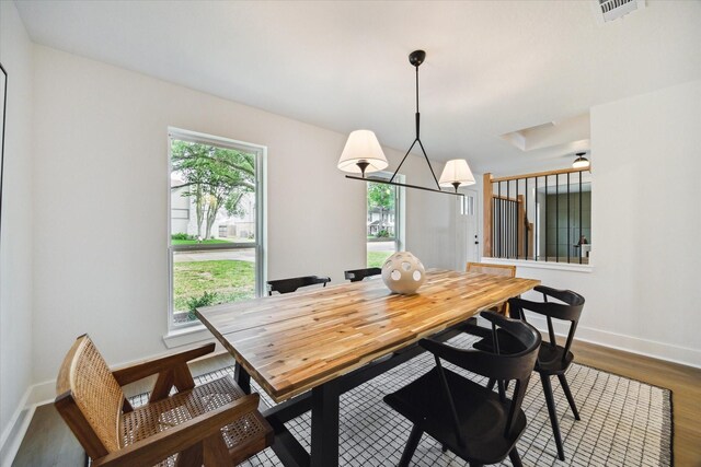 dining space featuring baseboards, wood finished floors, visible vents, and an inviting chandelier