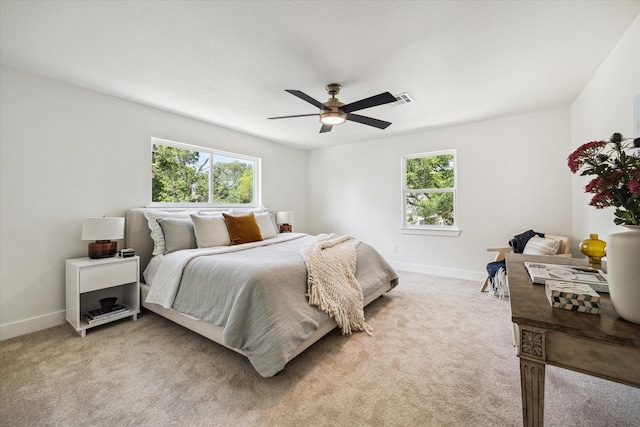 bedroom with baseboards, light colored carpet, and multiple windows