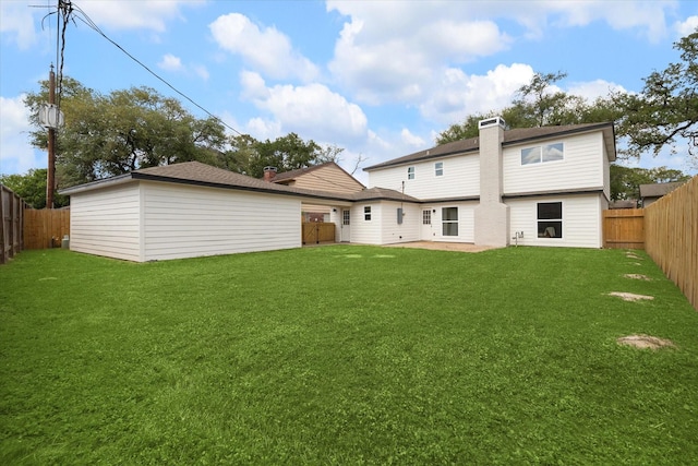 back of house featuring a fenced backyard, a chimney, and a yard
