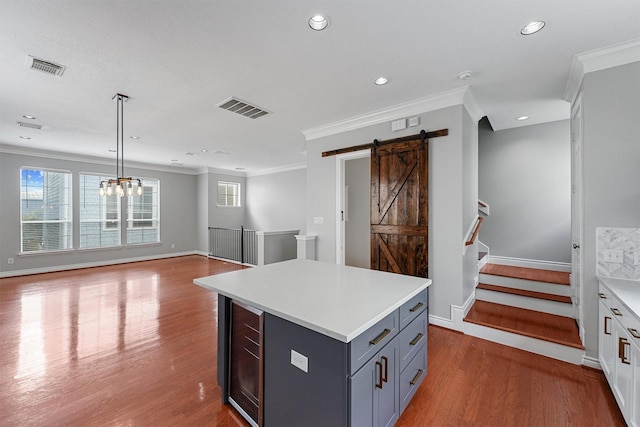 kitchen featuring a barn door, ornamental molding, and visible vents