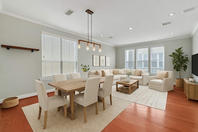 dining area with light wood-type flooring, visible vents, and ornamental molding