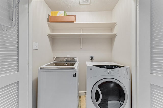 washroom with a textured ceiling, independent washer and dryer, and laundry area