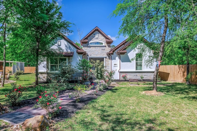 view of front of home featuring stone siding, a front lawn, and fence