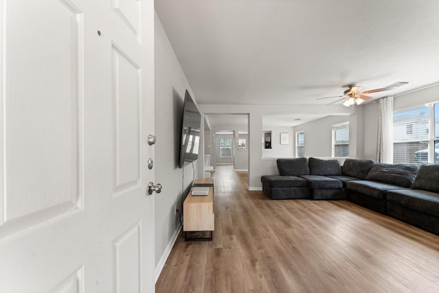 living room featuring light wood-type flooring, a ceiling fan, and baseboards