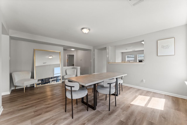 dining area featuring baseboards, wood finished floors, and visible vents