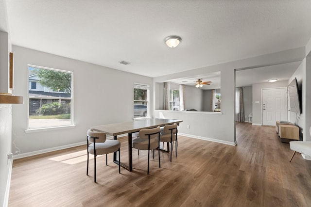 dining room with baseboards, wood finished floors, visible vents, and a ceiling fan