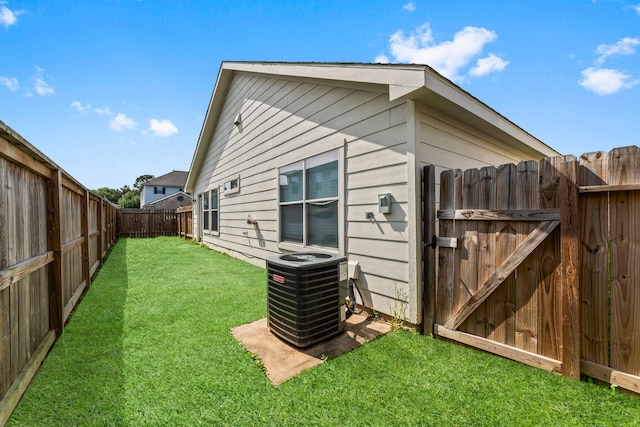 view of property exterior featuring a lawn, a fenced backyard, a gate, and central AC unit