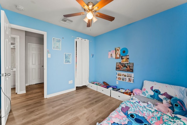 bedroom featuring baseboards, a ceiling fan, wood finished floors, and visible vents