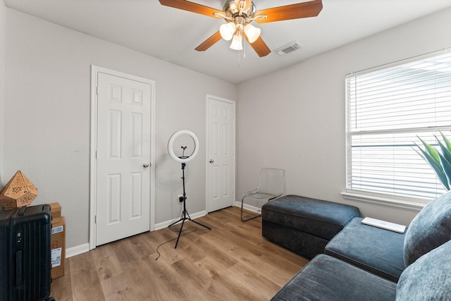 sitting room featuring light wood-style flooring, visible vents, a ceiling fan, and baseboards