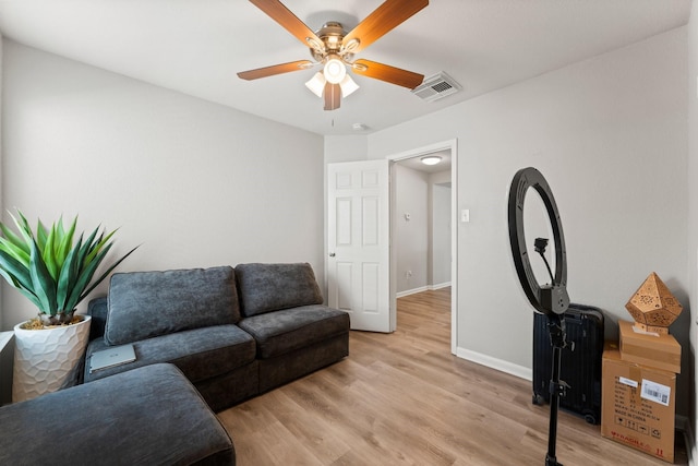 living area with baseboards, a ceiling fan, visible vents, and light wood-style flooring