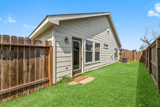back of house featuring a lawn, cooling unit, and a fenced backyard