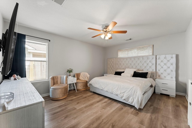 bedroom featuring wood finished floors, visible vents, a ceiling fan, and baseboards