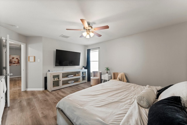 bedroom with wood finished floors, visible vents, baseboards, and ceiling fan