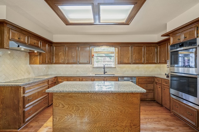 13018 Lentando Ln, Cypress, TX 77429 - kitchen featuring appliances with stainless steel finishes, under cabinet range hood, light wood-style floors, a sink, and a kitchen island