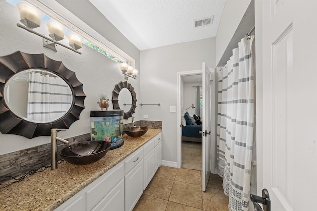 ensuite bathroom with double vanity, visible vents, tile patterned flooring, and a sink