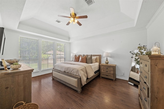 bedroom with a raised ceiling, a ceiling fan, visible vents, and dark wood finished floors