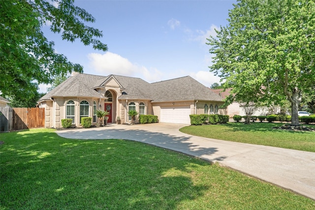 french country home with fence, an attached garage, brick siding, concrete driveway, and a front yard