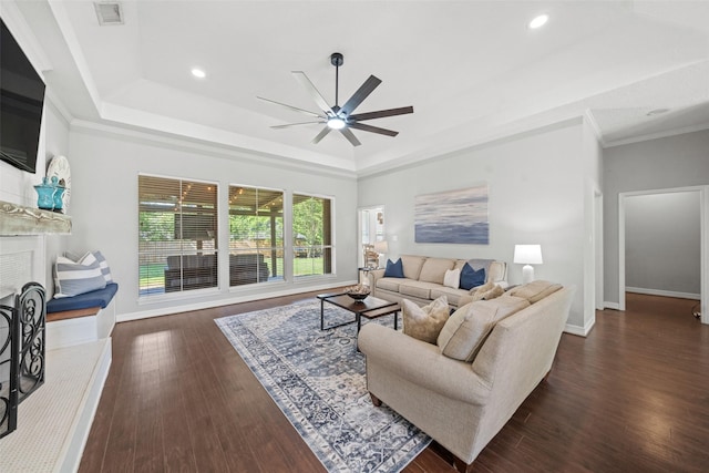 living room featuring a ceiling fan, baseboards, visible vents, dark wood-type flooring, and a raised ceiling