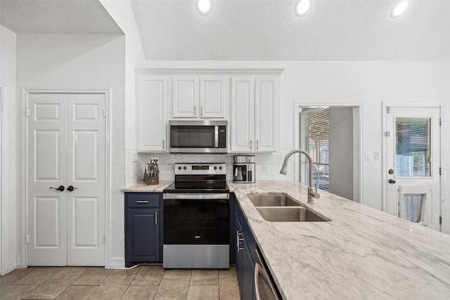 kitchen featuring light stone counters, white cabinets, appliances with stainless steel finishes, and a sink
