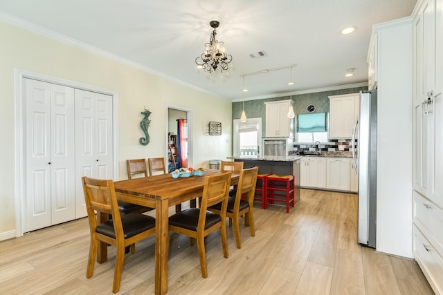 dining area featuring light wood-style flooring, visible vents, a notable chandelier, and ornamental molding