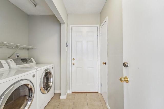 clothes washing area featuring baseboards, washer and clothes dryer, laundry area, and light tile patterned floors