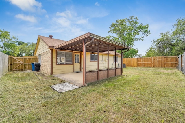 rear view of house featuring a lawn, a fenced backyard, a gate, and a patio