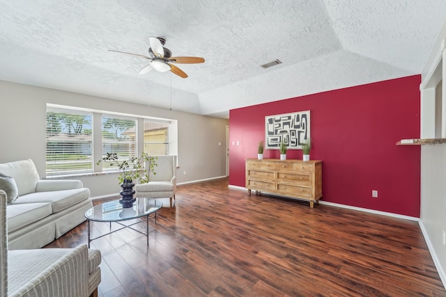 living area with a textured ceiling, visible vents, baseboards, a ceiling fan, and wood finished floors