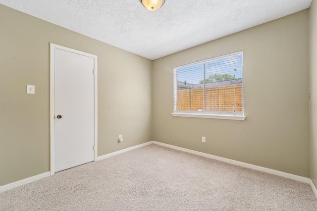 carpeted spare room with baseboards and a textured ceiling
