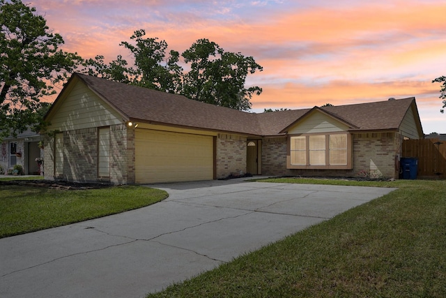 single story home featuring brick siding, an attached garage, a lawn, and driveway