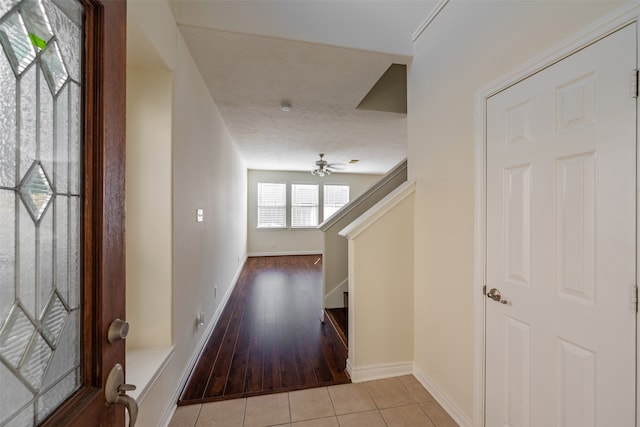 foyer entrance featuring baseboards, light tile patterned floors, and stairway
