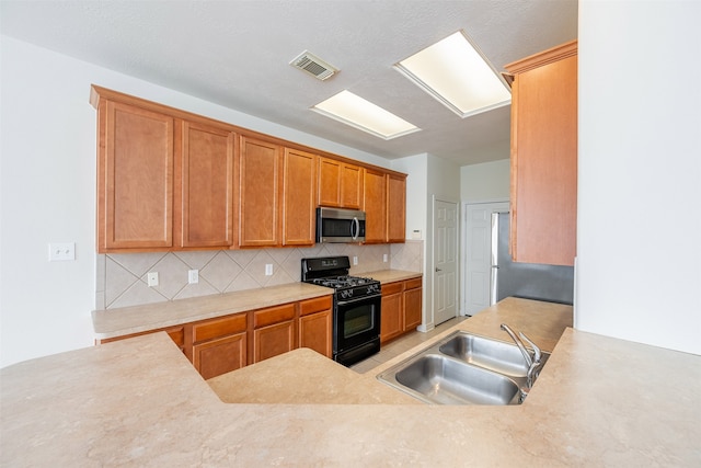 kitchen featuring a sink, backsplash, stainless steel appliances, and visible vents