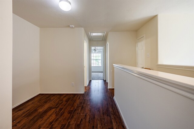 hallway with baseboards, dark wood finished floors, and attic access