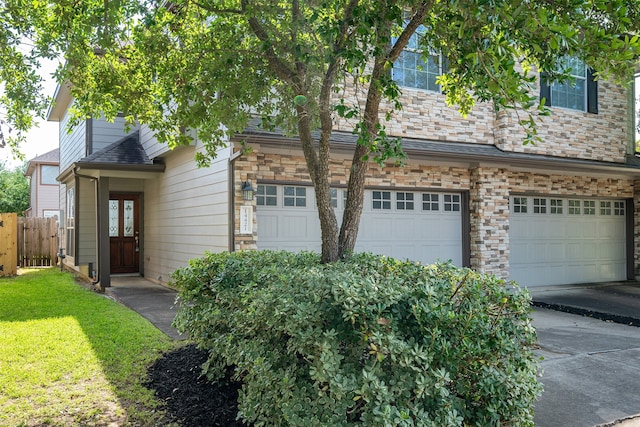view of front of property featuring an attached garage, fence, and stone siding