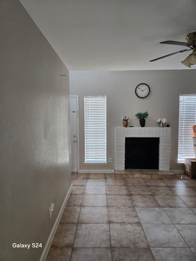 living room featuring baseboards, a ceiling fan, and a fireplace
