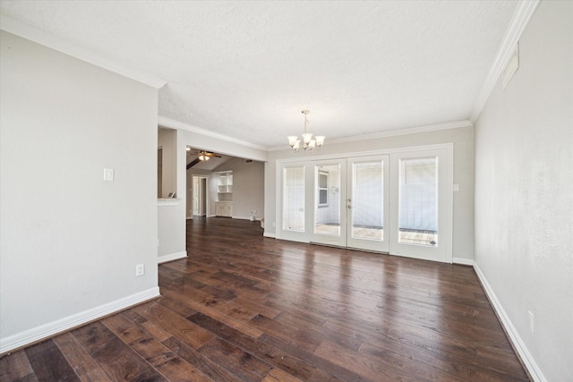 spare room featuring a chandelier, ornamental molding, dark wood finished floors, and baseboards