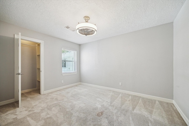 unfurnished bedroom featuring a spacious closet, carpet flooring, a textured ceiling, baseboards, and a closet
