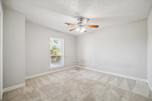 carpeted spare room featuring a ceiling fan, baseboards, and a textured ceiling