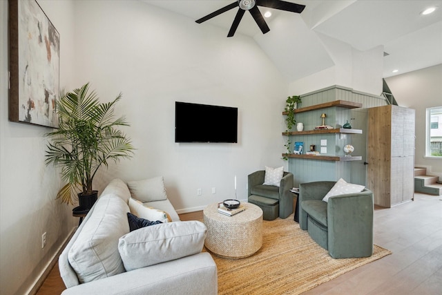 living room with ceiling fan, lofted ceiling, light wood-style floors, and baseboards