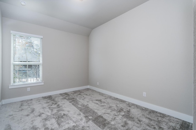 unfurnished room featuring carpet floors, vaulted ceiling, and baseboards