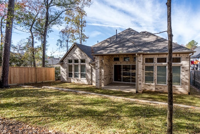 back of property with brick siding, fence, a patio area, and a lawn