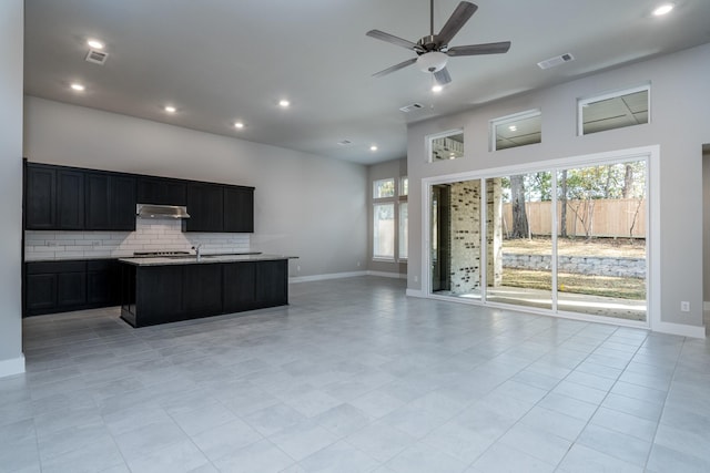 kitchen featuring open floor plan, visible vents, backsplash, ceiling fan, and under cabinet range hood
