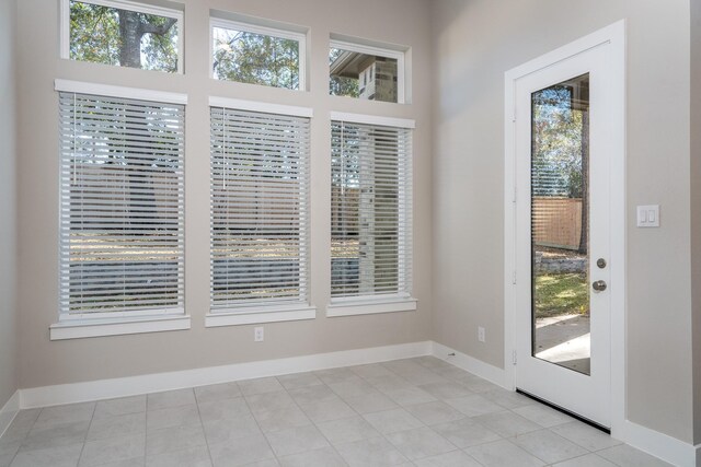 doorway to outside featuring baseboards and light tile patterned floors