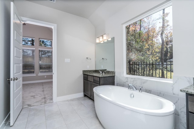 full bathroom with a freestanding tub, vanity, tile patterned floors, and plenty of natural light